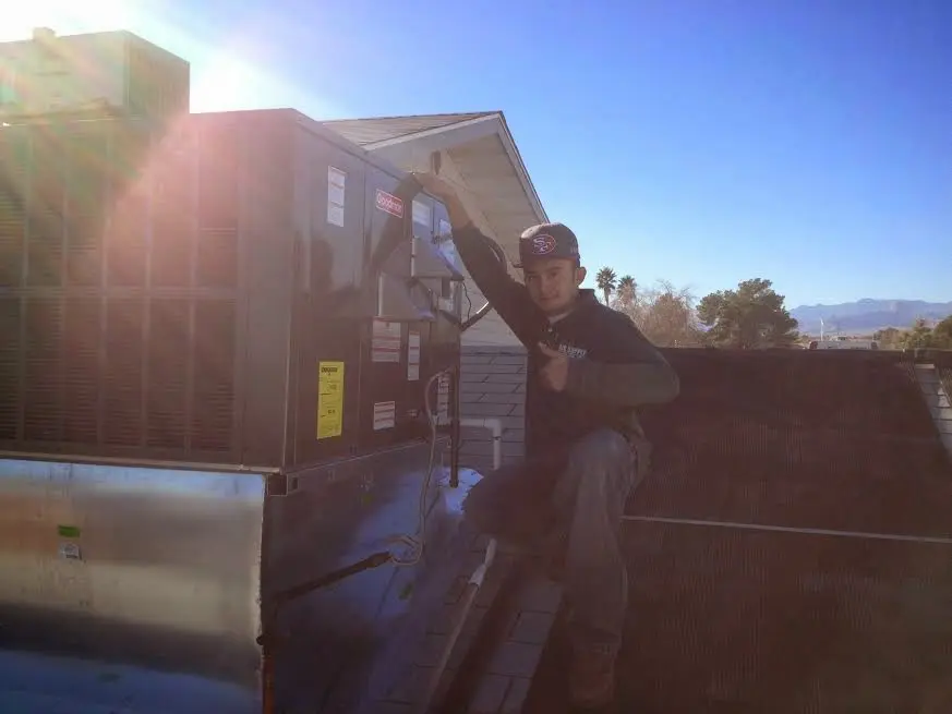 HVAC technician performing Air Duct Repair on a rooftop unit in Tahlequah